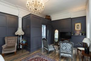 a living room with blue walls and chairs and a chandelier at The Warren Belfast in Belfast