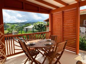 a wooden deck with a table and chairs on a balcony at Le ZANDOLI (Appartement avec vue) in Petit-Bourg