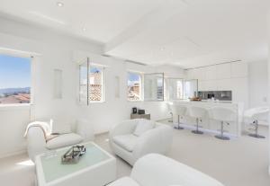 ein weißes Wohnzimmer mit weißen Stühlen und einem Tisch in der Unterkunft Traverse Des Artistes in Cannes