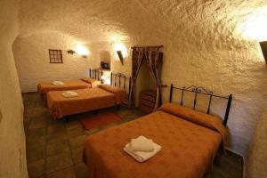 1 Schlafzimmer mit 3 Betten in einem Zimmer in der Unterkunft Alojamiento Cuevas Victoria in Galera
