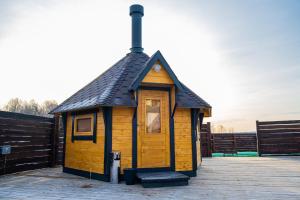 mały drewniany budynek z czarnym dachem w obiekcie Usadba Romashkovo Hotel w mieście Romashkovo