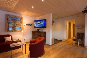 a living room with a couch and a tv on the wall at Appartement Seebachsee in Warth am Arlberg