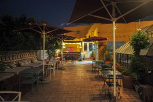 un patio con mesas, sillas y sombrillas por la noche en La Flamenka Hostel en Sevilla