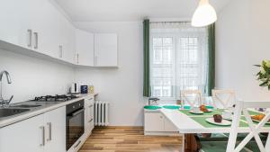 a kitchen with white cabinets and a kitchen table at Maya's Flats & Resorts - Old Town Długa 66 in Gdańsk