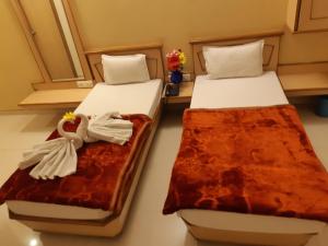 2 Betten in einem Hotelzimmer mit Handtüchern darauf in der Unterkunft Hotel Jay International in Vapi