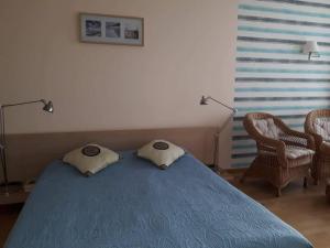 a bedroom with a blue bed and two chairs at Elijos apartamentai in Šventoji