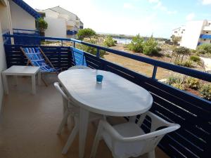 una mesa blanca y sillas en un balcón con vistas a la playa en Appartement T 2 AVEC PISCINE, en Lacanau