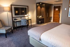 a hotel room with a bed and a desk and a television at Crow Wood Hotel & Spa Resort in Burnley