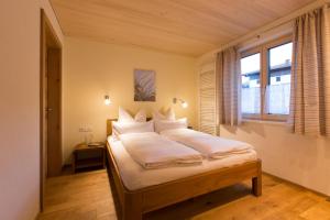 a bedroom with a bed with white sheets and a window at Appartement Seebachsee in Warth am Arlberg