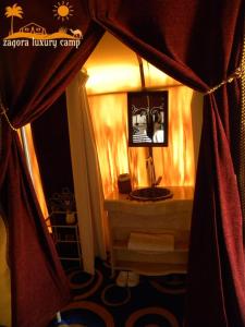 baño con lavabo en una habitación con cortinas en Sahara Luxury Camp en Zagora
