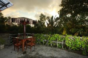 a table and chairs with an umbrella in a garden at Galle Paradise Inn in Galle
