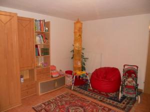 ein Wohnzimmer mit einem roten Stuhl und einem Bücherregal in der Unterkunft Appartement Huber in Lutzmannsburg