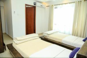 two beds in a room with a window at Hillview Apartments in Kampala +4 photos