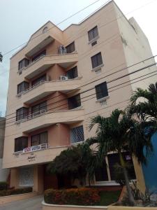 a building with a palm tree in front of it at Apartamento rodadero playa y diversion in Santa Marta