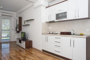 a kitchen with white cabinets and a wooden floor at Apartments Villa Zora in Star Dojran