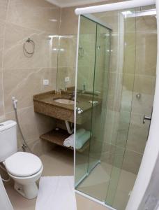 a bathroom with a shower and a toilet and a sink at Pousada Praia Brava in Matinhos