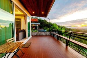 a balcony of a house with a wooden bench at Ao Luek Panoramic Pool-SHA Plus in Ao Luk