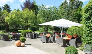 eine Terrasse mit Tischen, Stühlen und einem Sonnenschirm in der Unterkunft Bundt's Hotel & Gartenrestaurant in Hamburg