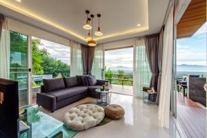 a living room with a couch and large windows at Ao Luek Panoramic Pool-SHA Plus in Ao Luk