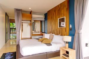 a bedroom with a large white bed with blue walls at Ao Luek Panoramic Pool-SHA Plus in Ao Luk