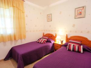 two beds in a bedroom with purple sheets and a window at Holiday Home Vicky by Interhome in Riumar +7 photos