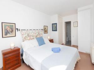 a bedroom with a white bed and a wooden dresser at Apartment Front Beach by Interhome in Calafell