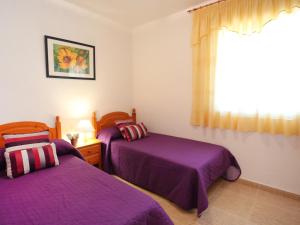 a bedroom with two beds with purple sheets and a window at Holiday Home Vicky by Interhome in Riumar