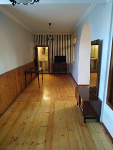 um quarto vazio com piso em madeira e uma mesa em Hope Lake city Apartment em Zaqatala