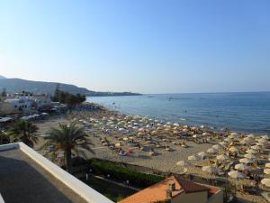 a beach with a lot of umbrellas and the water at Vlachakis Hotel in Stalida