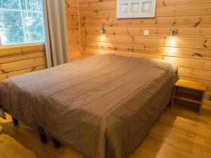 ein Schlafzimmer mit einem Bett in einer Holzwand in der Unterkunft Holiday Home Tintintupa by Interhome in Tahkovuori