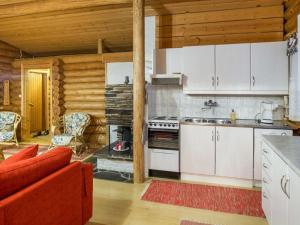 a kitchen with white cabinets and a red couch at Holiday Home Honkakeko by Interhome in Sirkka