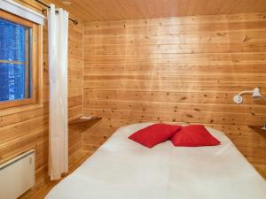 una camera da letto con pareti in legno e un letto con cuscini rossi di Holiday Home Honkakeko by Interhome a Levi Altre 24 foto