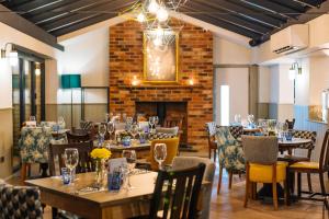 a dining room with tables and chairs and a fireplace at The Eaton Oak in Saint Neots