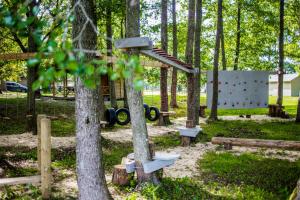 un parque infantil con árboles y una pared de roca en Kempings Usmas Meķi, en Renda