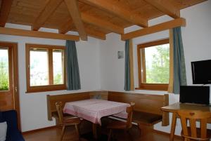 een eetkamer met een tafel en twee ramen bij Aria d'Bosch in Badia