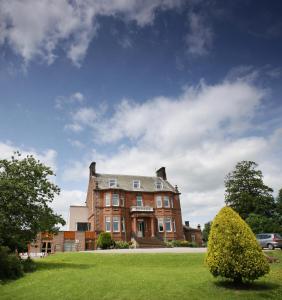 a large brick house on a green lawn at Cressfield Country House Hotel in Ecclefechan