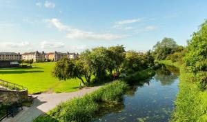 a river in a park with people walking along it at The Polwarth Apartment in Edinburgh