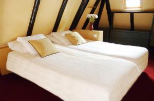 a large white bed with two pillows on it at Hotel de Vischpoorte, centrum Deventer en aan de IJssel in Deventer