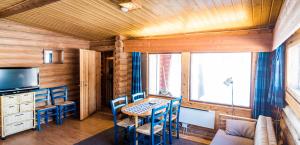 une salle à manger avec une table, des chaises et une télévision dans l'établissement Ukonjärven Holiday Village, à Ivalo
