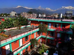 un edificio de apartamentos con ventanas coloridas con montañas en el fondo en New Pokhara Lodge - Lakeside, Pokhara Nepal, en Pokhara