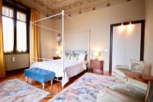 ein Schlafzimmer mit einem Himmelbett und einem blauen Stuhl in der Unterkunft Villa Farinelli in Cadegliano Viconago