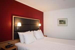 Ce lit se trouve dans une chambre d'hôtel dotée d'un mur rouge. dans l'établissement Hotel Restaurant Het Witte Huis, à Olterterp
