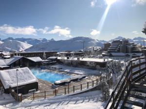 a resort with a swimming pool in the snow at Appartement cozy centre Alpe d'Huez in L'Alpe-d'Huez