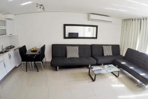 a living room with a black couch and a table at Eilat Family Apartment Garden & Free Parking in Eilat