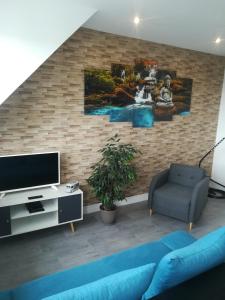 a living room with a blue couch and a tv at Le Sleepway Lorient in Lorient