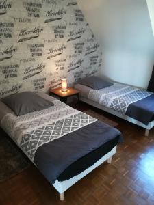 two beds in a room with a wall covered in signatures at Le Sleepway Lorient in Lorient