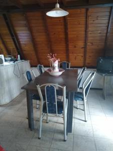 una mesa de comedor con sillas y un jarrón de flores. en chalet de montaña en Barreal