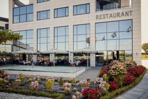 a restaurant with umbrellas and flowers in front of a building at Van der Valk Hotel Tiel in Tiel