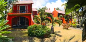 a red house with a palm tree in front of it at Flowers of Paradise in Mont Choisy