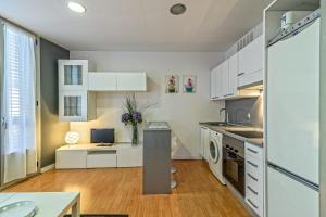 una cocina con armarios blancos y un escritorio. en Loft en Badalona Centro, en Badalona